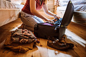 Unrecognizable woman packing luggage in log cabin