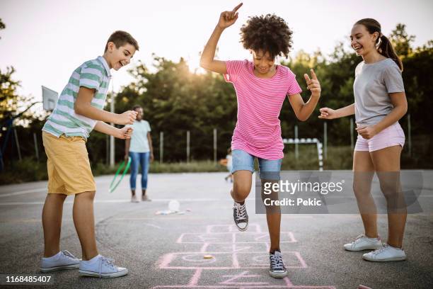 fröhliche kinder spielen hopscotch auf schulhof - children playing in yard stock-fotos und bilder