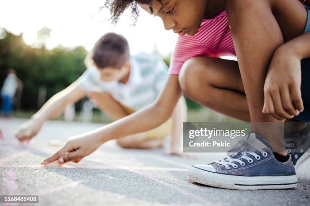 african girl drawing hopscotch on asphalt with friends - hopscotch stock pictures, royalty-free photos & images