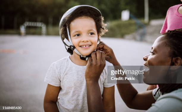 mom helping little girl with protective helmet - helmet stock pictures, royalty-free photos & images
