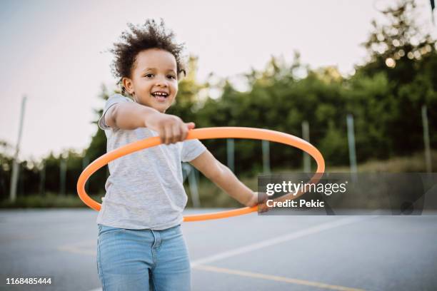 happy little girl with plastic hoop on playground - plastic hoop stock pictures, royalty-free photos & images