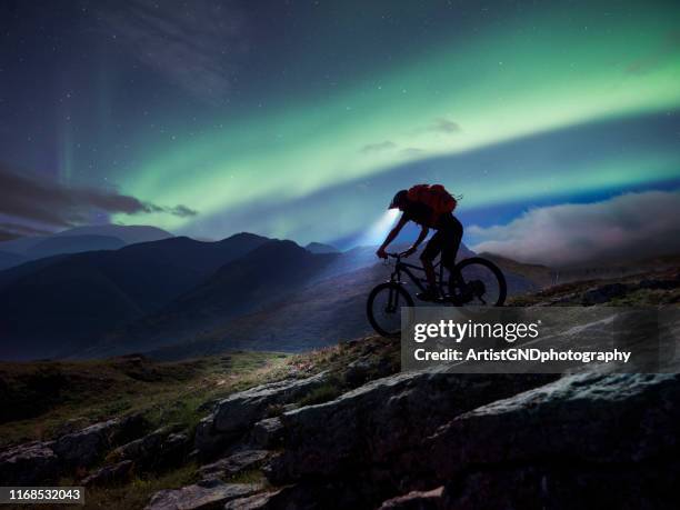 mountainbiker, der in den bergen unter aurora polaris reitet. - fahrrad nacht stock-fotos und bilder