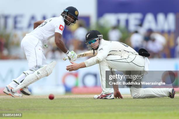 Tom Latham of New Zealand attempts to stop a ball Lahiru Thirimanne of Sri Lanka looks during day three of the First Test match between Sri Lanka and...