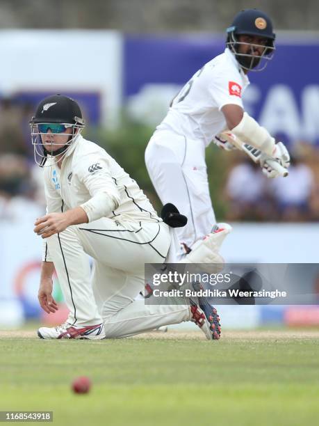 Tom Latham of New Zealand attempts to stop a ball Lahiru Thirimanne of Sri Lanka runs during day three of the First Test match between Sri Lanka and...