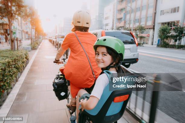 mother cycling home with her preschool child at sunset in tokyo - famille a velo photos et images de collection