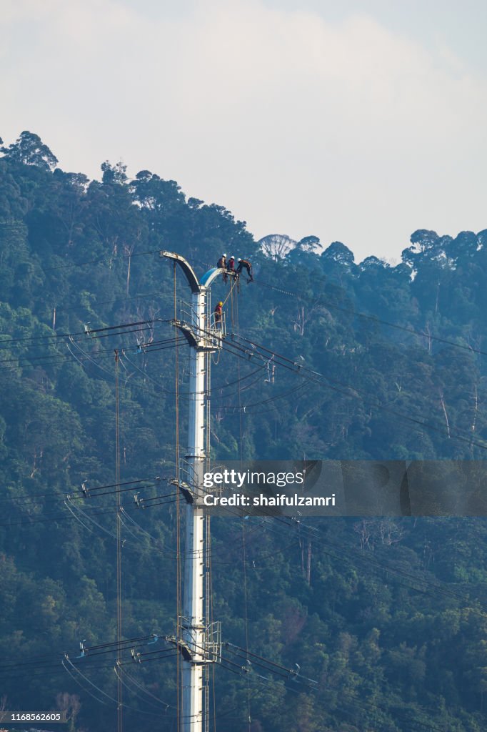 Workers working on power pole at sub urban area of Kuala Lumpur, Malaysia.