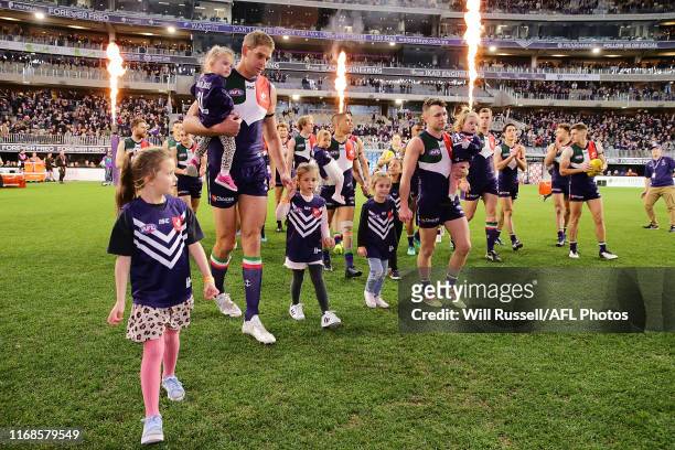 The milestone men walk out with their kids during the round 22 AFL match between the Fremantle Dockers and the Essendon Bombers at Optus Stadium on...