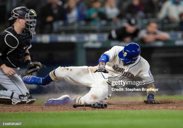 Keon Broxton of the Seattle Mariners slides safely into home plate in front of catcher Zack Collins of the Chicago White Sox to score on a single by...