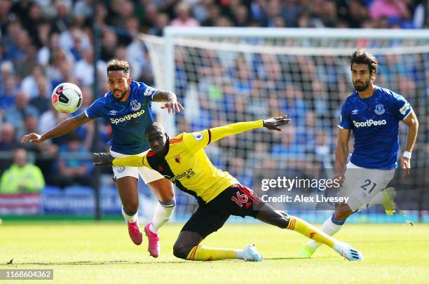 Abdoulaye Doucoure of Watford falls in a battle with Theo Walcott and Andre Gomes of Everton during the Premier League match between Everton FC and...