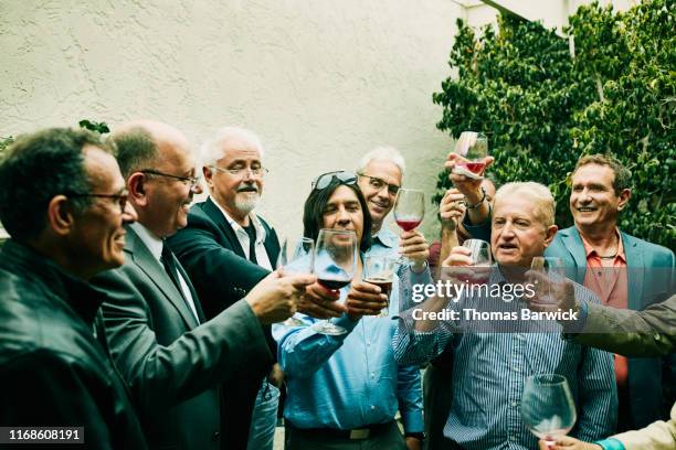 mature and senior men toasting during cocktail party - 60s cocktail party stock-fotos und bilder