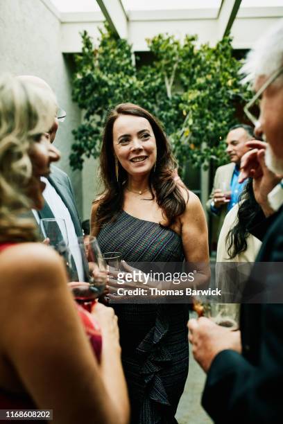 smiling mature woman in discussion with friends during cocktail party - 4 cocktails stock pictures, royalty-free photos & images