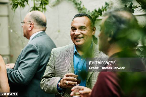 Mature man laughing with friend during cocktail party