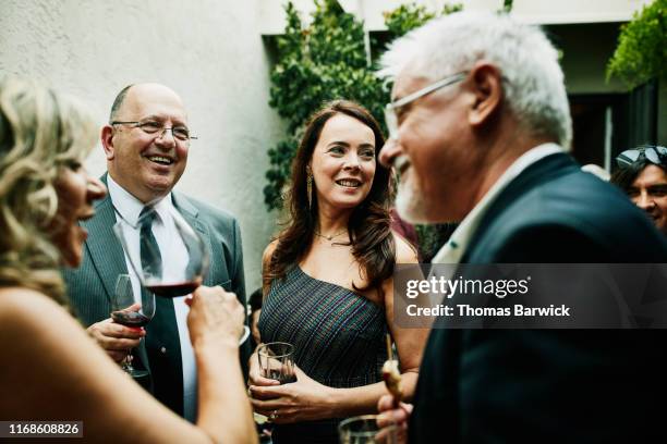 Smiling and laughing friends in discussion during cocktail party