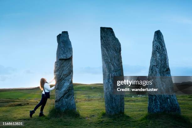 weibliche touristen blicken auf ein trio von hohen felsen an den berühmten calanais standing stones, outer hebrides, isle of lewis, schottland, uk. - keltisch stock-fotos und bilder