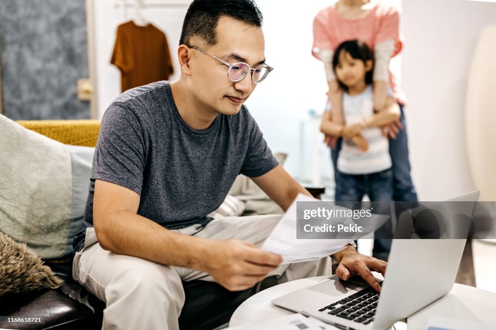 Man working at home while wife and daughter playing