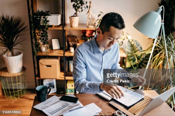 young man calculating his home expenses - mid adult men stock pictures, royalty-free photos & images