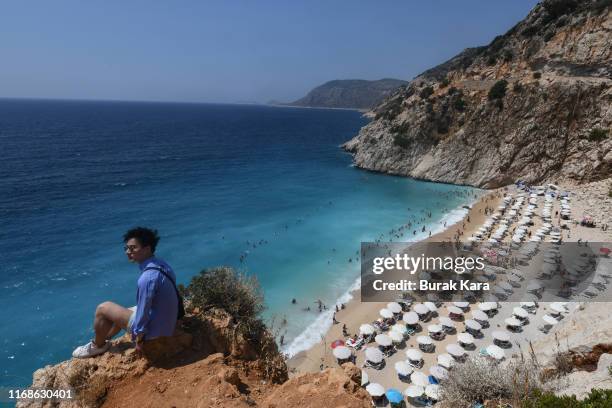 Tourist sits on the rocks in Kaputas beach on August 17, 2019 in Kas, Turkey. Turkey’s resort towns saw a 100 percent occupancy rate with the Eid...