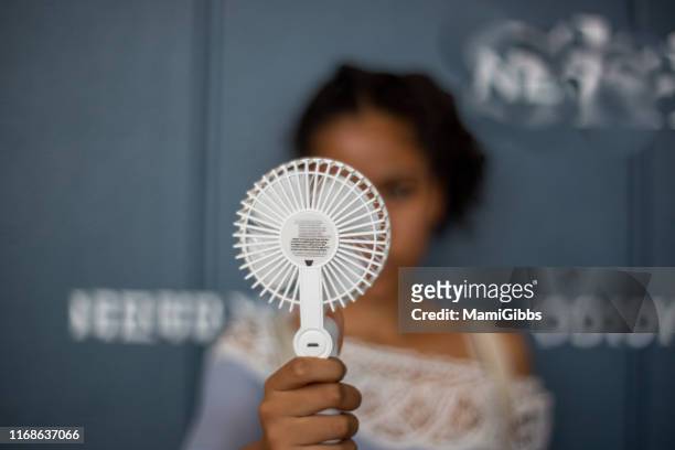 a girl uses a handy fan at the hopping mall - ventilator stock-fotos und bilder