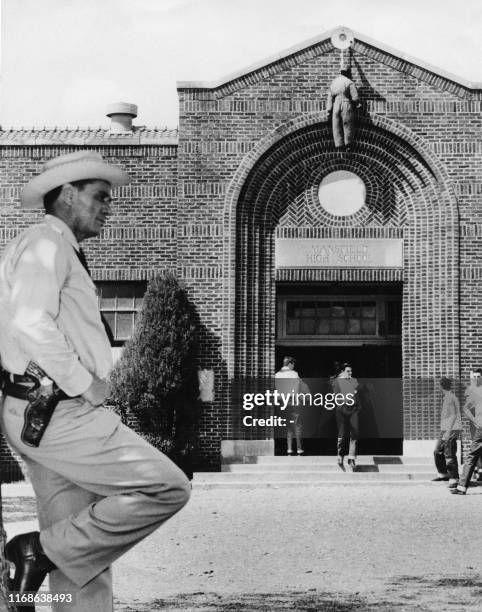 To protest against the registration of African-Americans students in school, an African-American effigy is suspended above the school entrance, under...