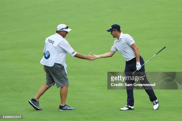Justin Thomas of the United States celebrates with his caddie Jimmy Johnson after his eagle on the 16th hole during the third round of the BMW...