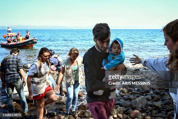 Migrants with a child, helped by rescuers arrive on the Greek island of Lesbos after crossing the Aegean Sea from Turkey, on September 16, 2019....