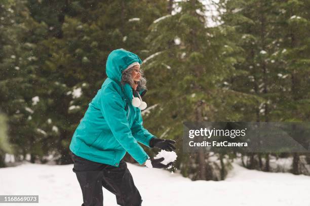 senior woman holding up a giant snowball in the forest - giant camera stock pictures, royalty-free photos & images