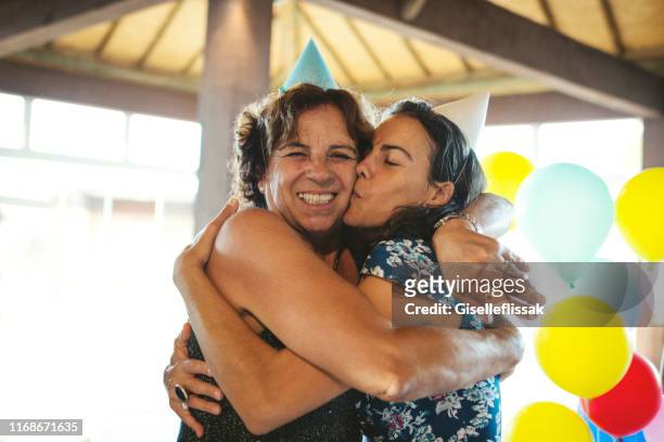 mother and daughter embracing and celebrating a birthday party using party hat - surprise birthday party stock pictures, royalty-free photos & images