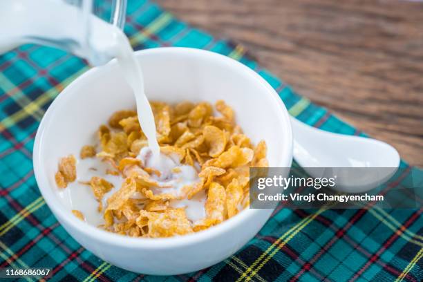 milk splashes into corn flakes bowl - cereali da colazione foto e immagini stock