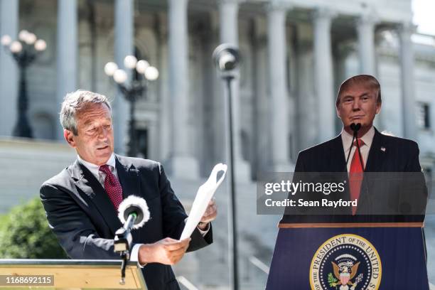 Former South Carolina Gov. Mark Sanford speaks to the media with a cardboard cutout of President Donald Trump during a campaign stop at the state...