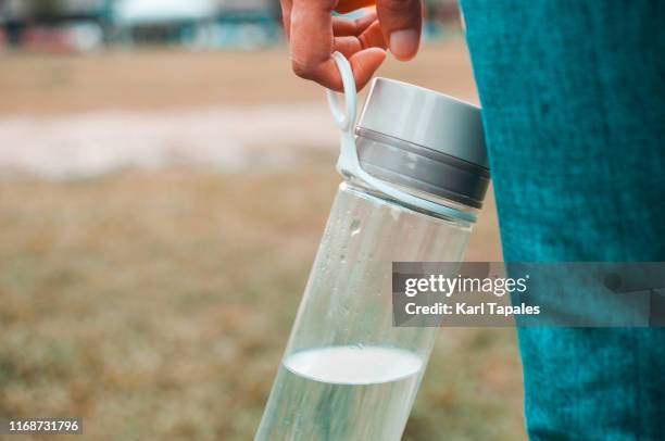 a young woman wearing a casual clothing is holding a reusable water bottle container while outdoor - reusable 個照片及圖片檔