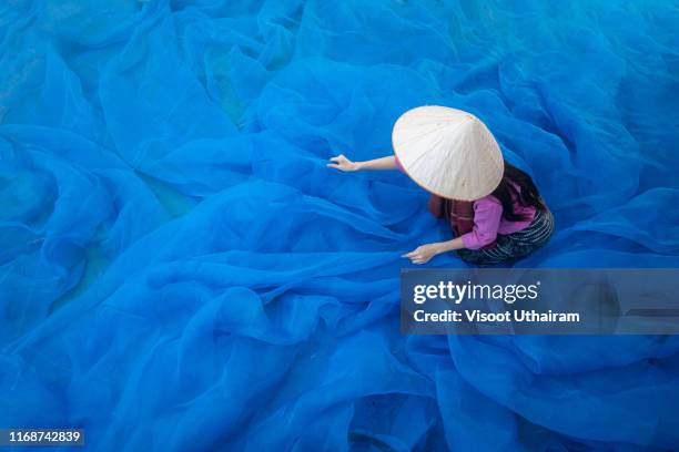 beautiful woman are cleaning the fishing nets at lake. - association of southeast asian nations stock pictures, royalty-free photos & images