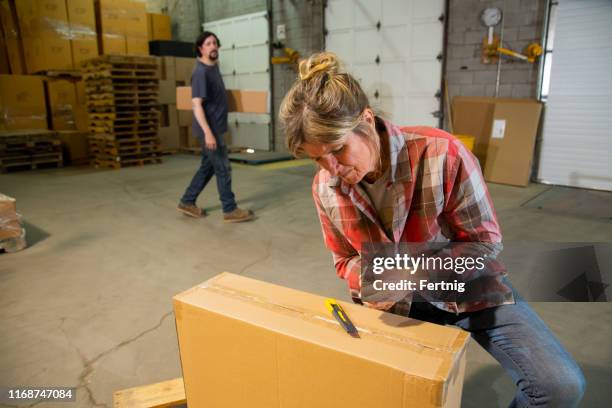 een industrieel werkplek magazijn veiligheid onderwerp.  een vrouwelijke werknemer met een mes letsel van een box cutter. - utility knife stockfoto's en -beelden
