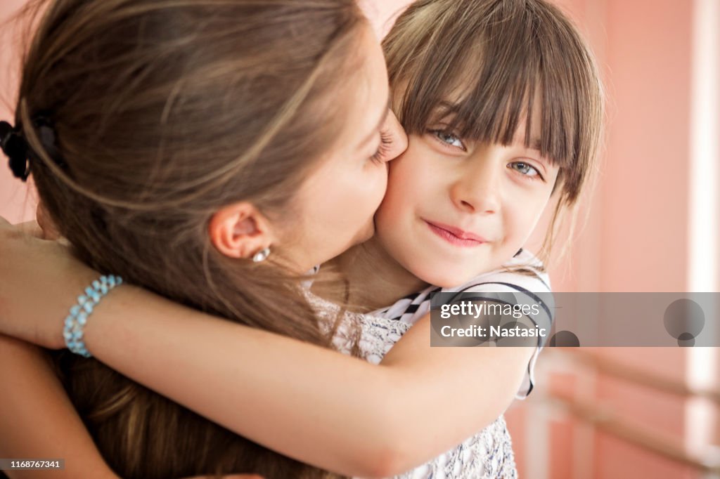 Liefdevolle moeder en dochter knuffelen, kijken naar camera