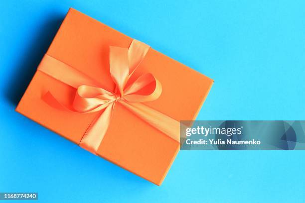 craft paper gift with orange ribbon on dark blue background with copy space. - gift box top stock pictures, royalty-free photos & images