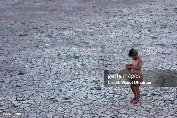 asia children standing on cracked earth in the arid area. - thirsty photos et images de collection