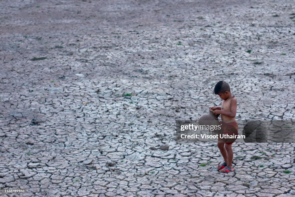 Asia children standing on cracked earth in the arid area.