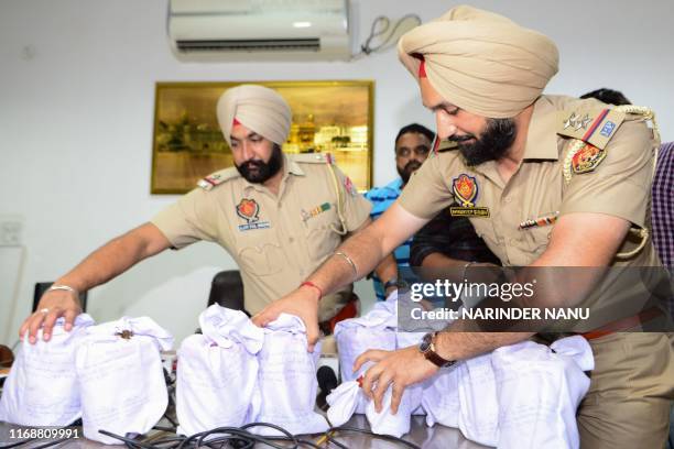 Indian police display bags containing 13.72kg of heroin recovered in the India-Pakistan border village of Daoke, when a smuggler was also arrested,...