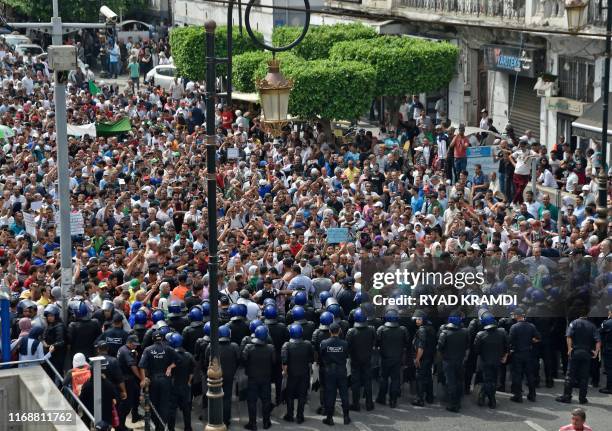 Algerian security forces form a human barrier in front of demonstrators taking part in a rally in the streets of the capital Algiers on September 17,...