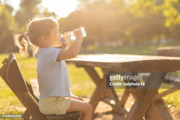 bambina che beve acqua all'aperto - sunlight through drink glass foto e immagini stock