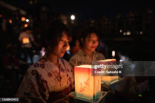 young adulte sisters holding lantern for floating at summer night event - obon stock pictures, royalty-free photos & images
