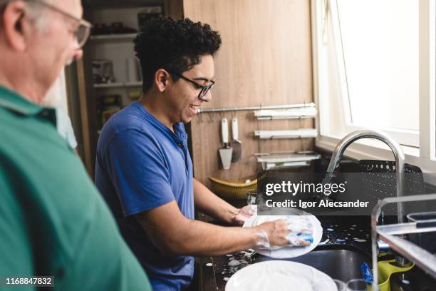 teen boy washing dishes with his grandfather - wash the dishes stock pictures, royalty-free photos & images