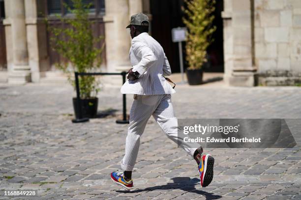 Guest wears a white seersucker suit with cuffed pants, a cap, colorful Nike sneakers, outside Thom Browne, during Paris Fashion Week - Menswear...