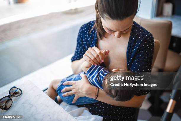 mère allaitant son bébé en public - bâtiment public photos et images de collection
