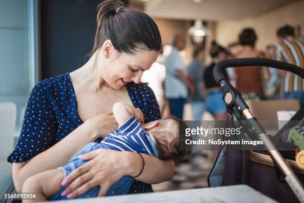 mère allaitant son bébé en public - femme poussette rue photos et images de collection