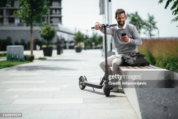 businessman using phone while on electric scooter - push scooter stock pictures, royalty-free photos & images