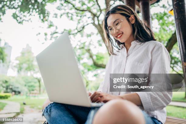 studentin mit laptop im park - female spectacles stock-fotos und bilder