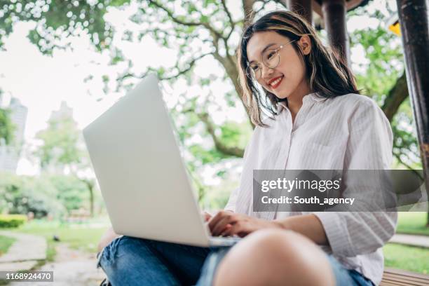 woman student using laptop in park - vietnamese ethnicity imagens e fotografias de stock