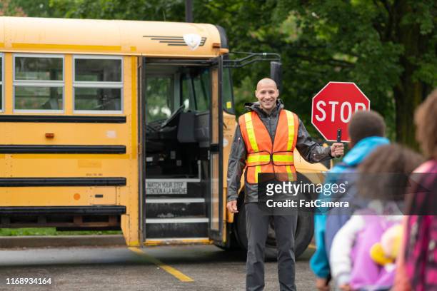 笑顔の横断ガードは、学生が安全にスクールバスに乗るのに役立ちます - 交通誘導員 ストックフォトと画像