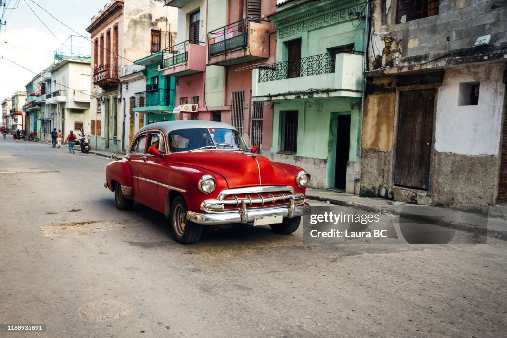 Red vintage car driving in Havana.