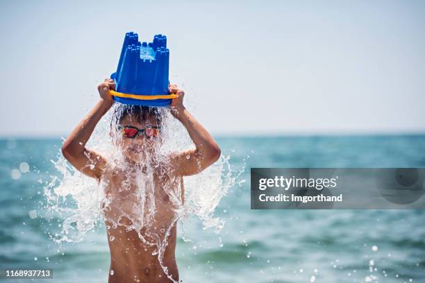 little boy cooling himself with bucket of water - beach bucket stock pictures, royalty-free photos & images